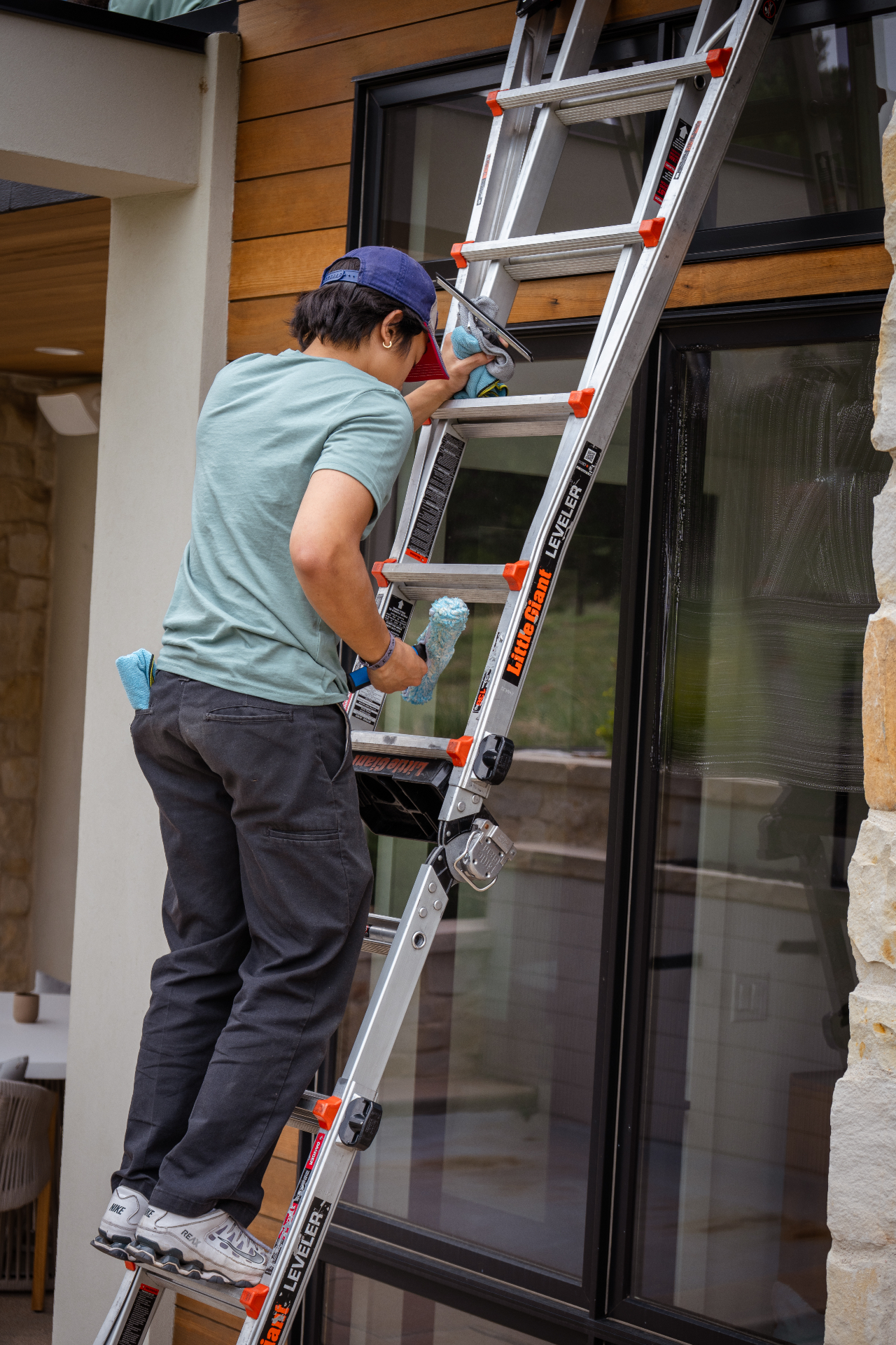 Technician squeegeeing a large window from a ladder